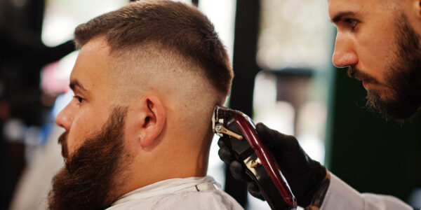 Handsome bearded man at the barbershop, barber at work.